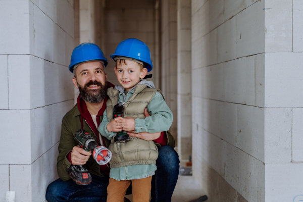 Father and his little son working together on their unfinished house.