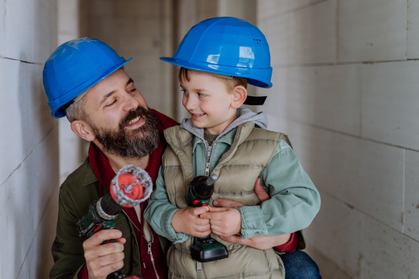 Father and his little son working together on their unfinished house.