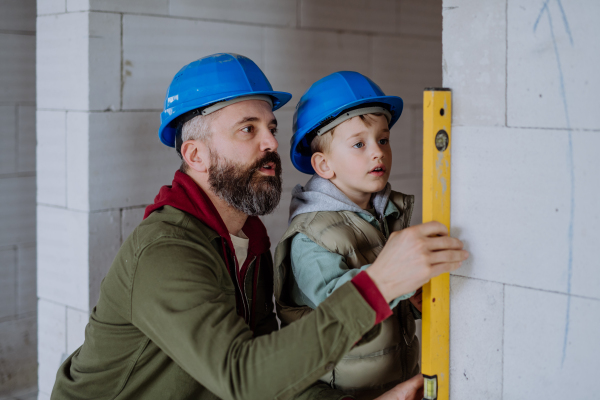 Father and his little son working together on their unfinished house.