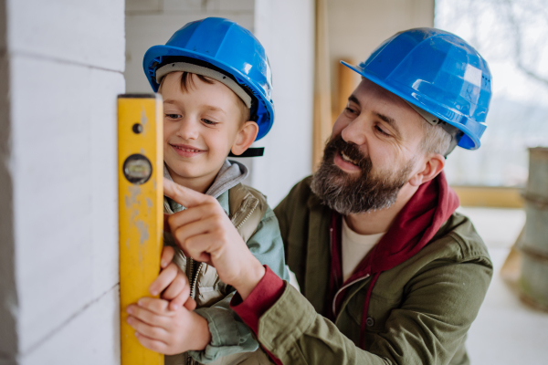 Father and his little son working together on their unfinished house.