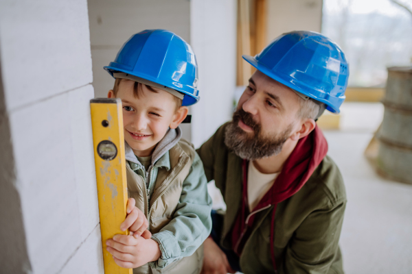 Father and his little son working together on their unfinished house.