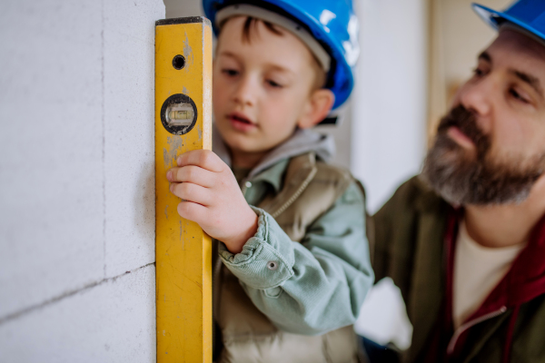 Father and his little son working together on their unfinished house.