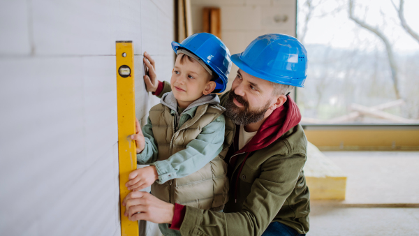 Father and his little son working together on their unfinished house.