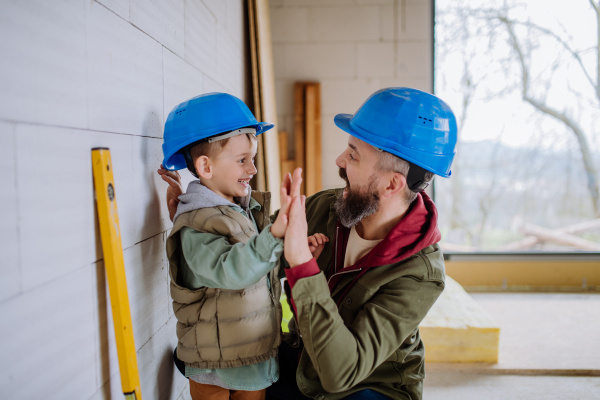 Father and his little son working together on their unfinished house.