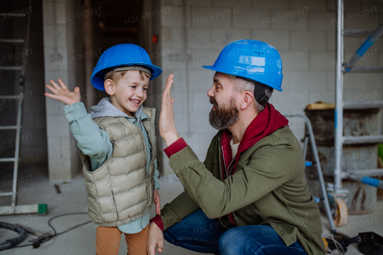 Father and his little son working together on their unfinished house.