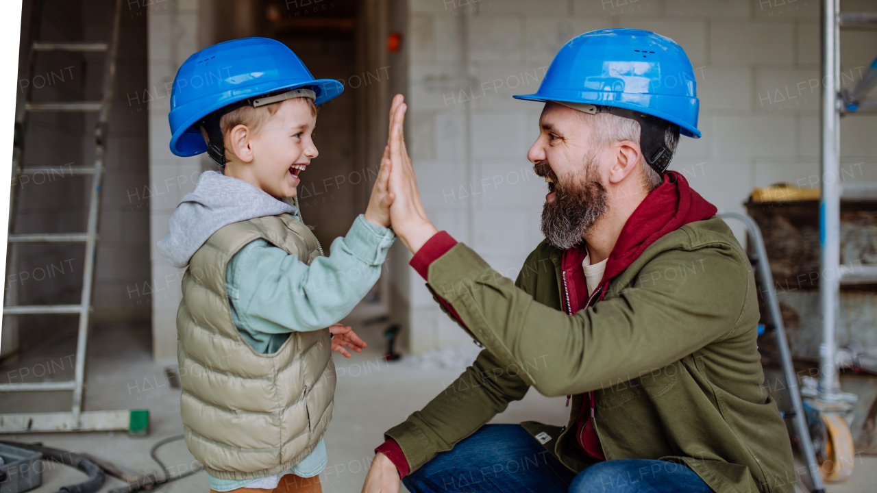 Father and his little son working together on their unfinished house.