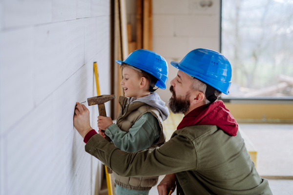 Father and his little son working together on their unfinished house.