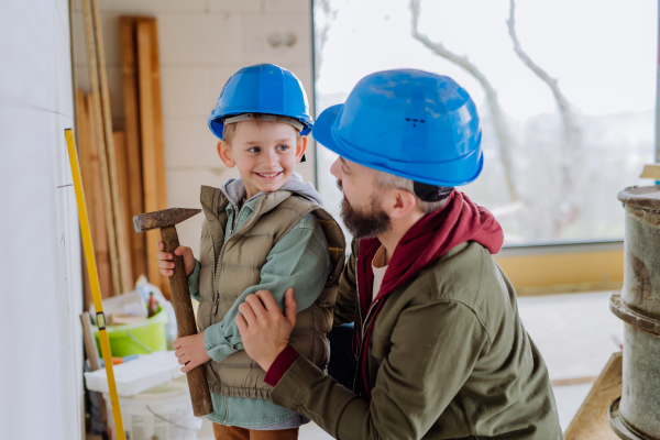 Father and his little son working together on their unfinished house.