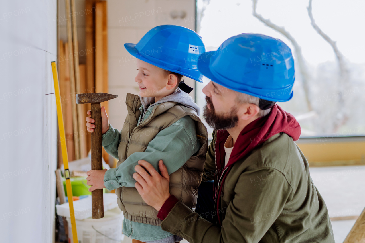 Father and his little son working together on their unfinished house.