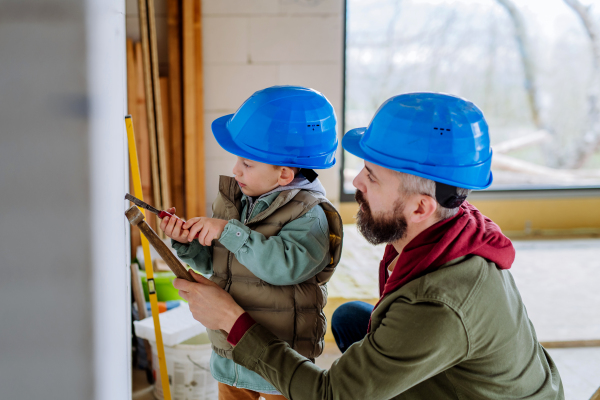 Father and his little son working together on their unfinished house.