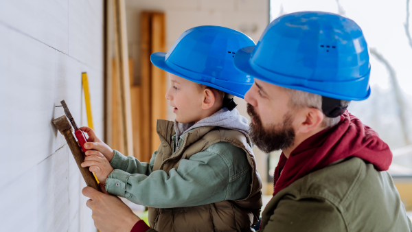 Father and his little son working together on their unfinished house.