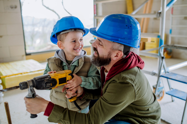 Father and his little son working together on their unfinished house.