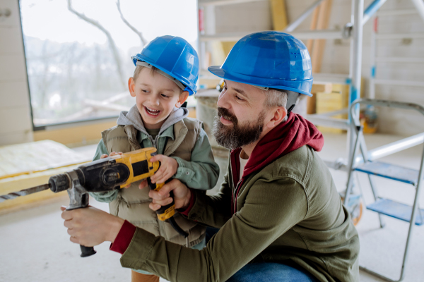 Father and his little son working together on their unfinished house.