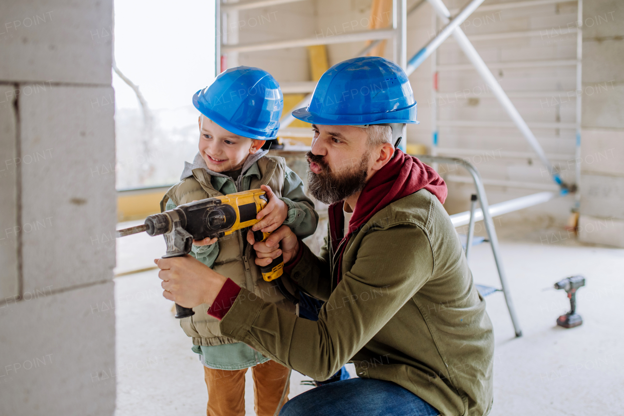 Father and his little son working together on their unfinished house.