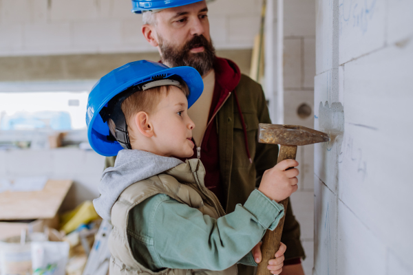 Father and his little son working together on their unfinished house.