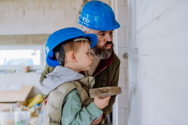 Father and his little son working together on their unfinished house.