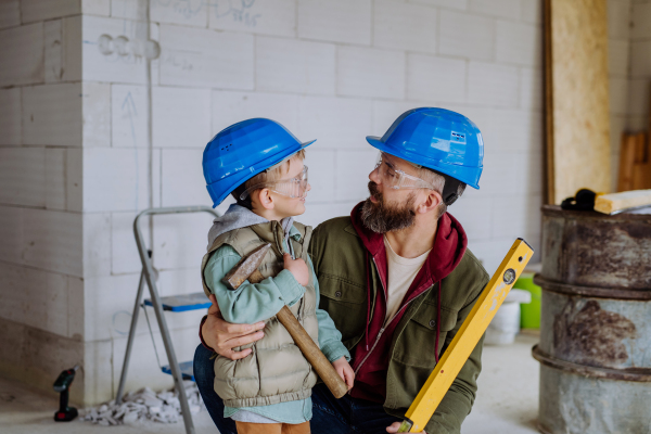 Father and his little son working together on their unfinished house.