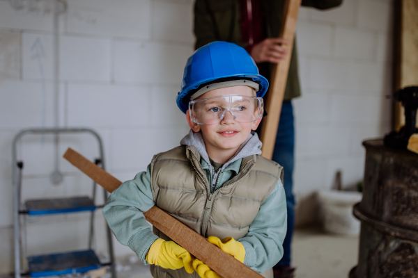 Little boy helping his father in their unfinished house.