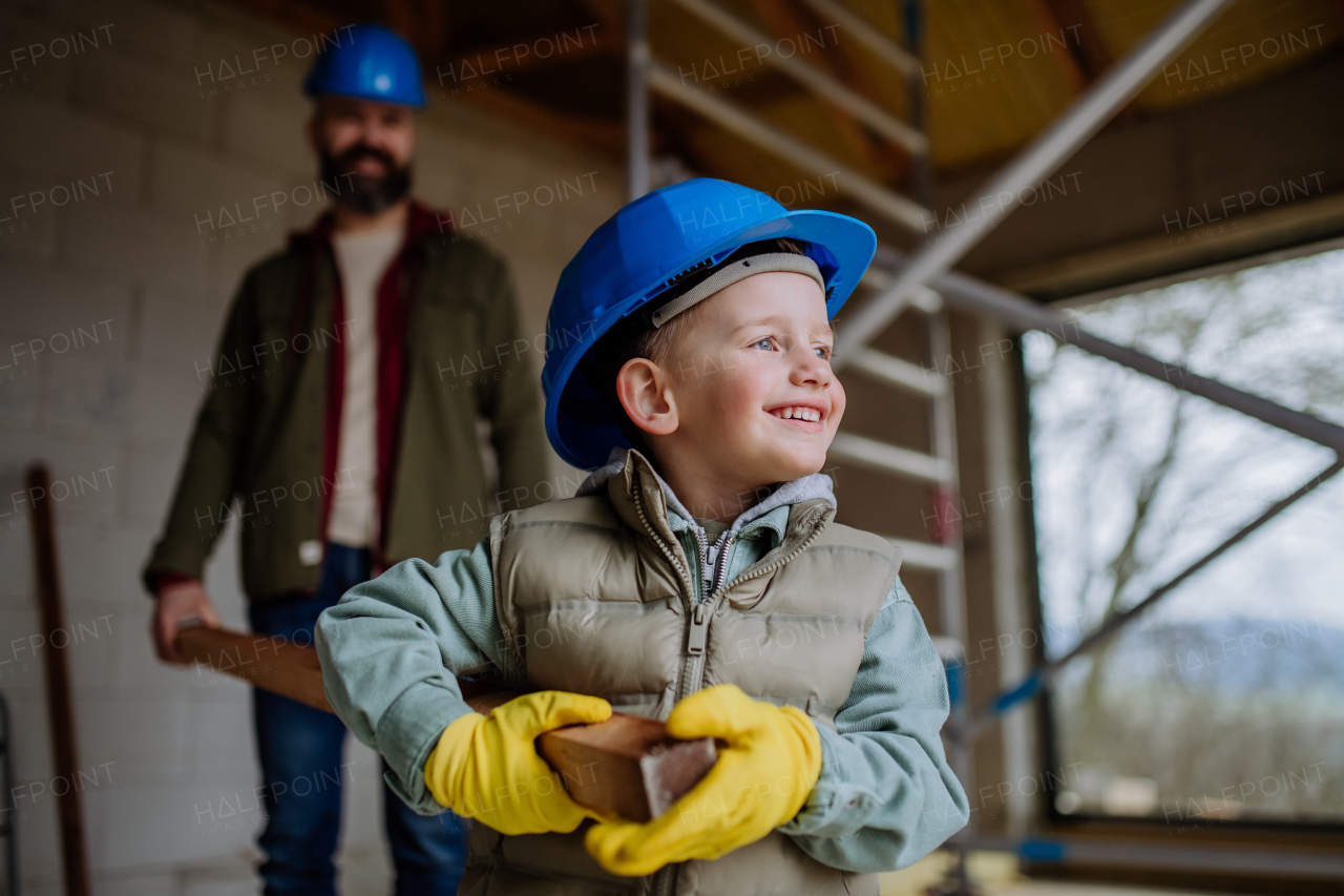 Father and his little son working in front of their unfinished house, carring a wooden panicle.