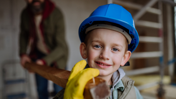 Father and his little son working in front of their unfinished house, carring a wooden panicle.