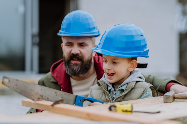 Father and his little son working together in front of their unfinished house.