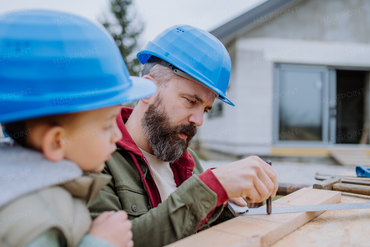 Father and his little son working together in front of their unfinished house.