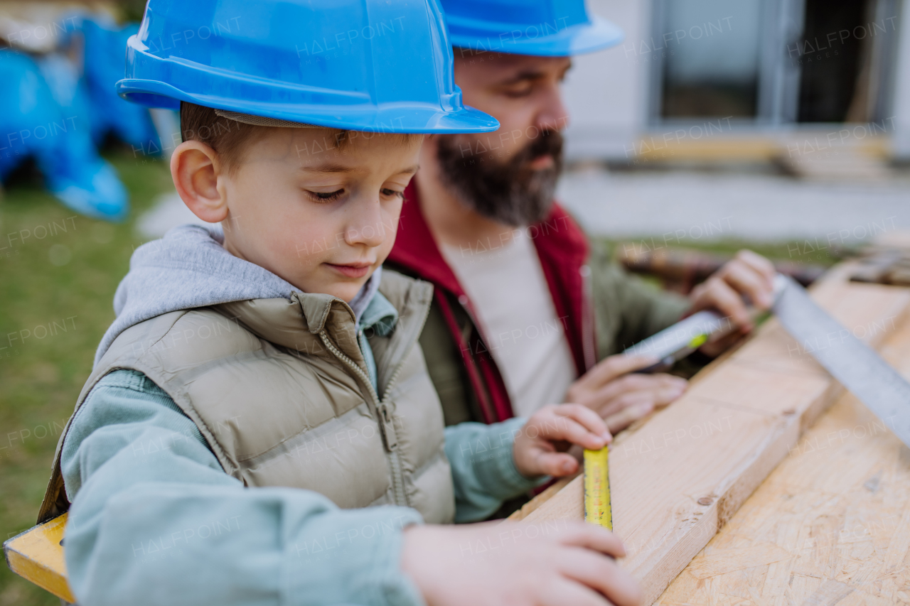 Father and his little son working together in front of their unfinished house.