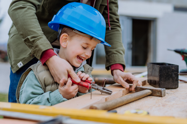 Father and his little son working together in front of their unfinished house.