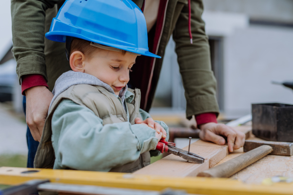 Father and his little son working together in front of their unfinished house.