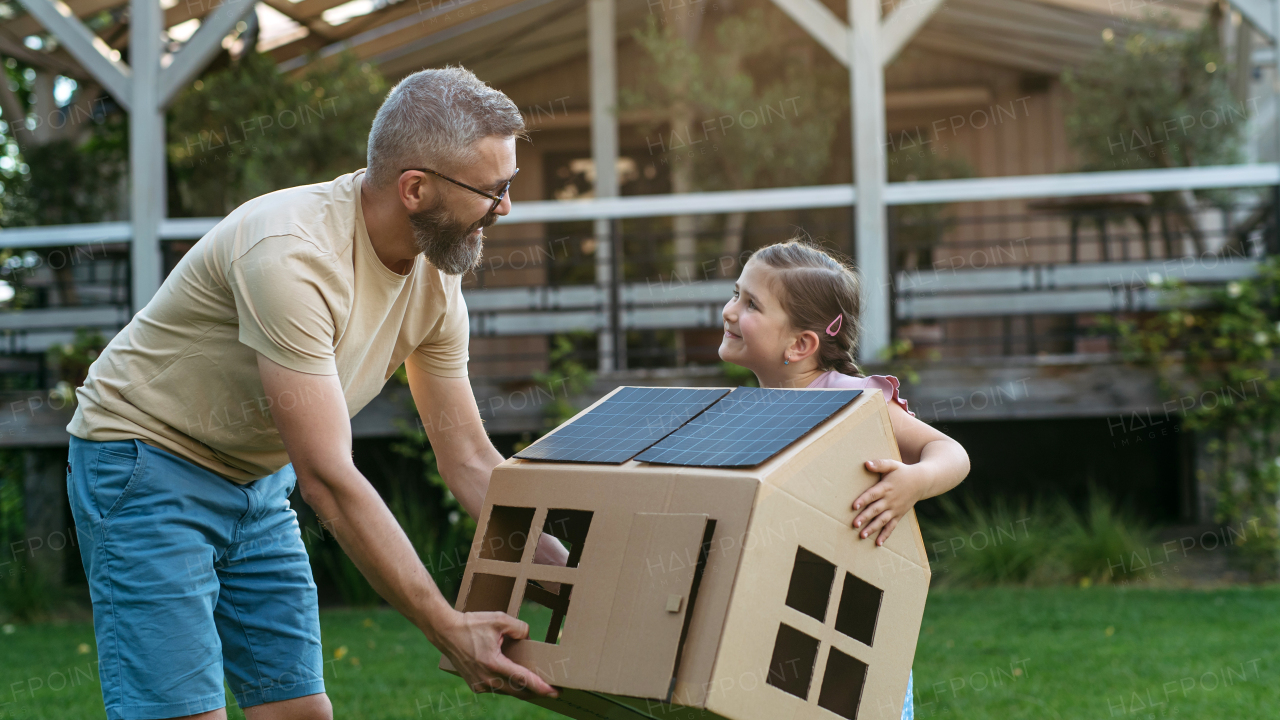 Dad and girl playing with house with solar panels on roof, learning about solar energy. Rooftop solar or photovoltaic system. Sustainable future for next generation concept.