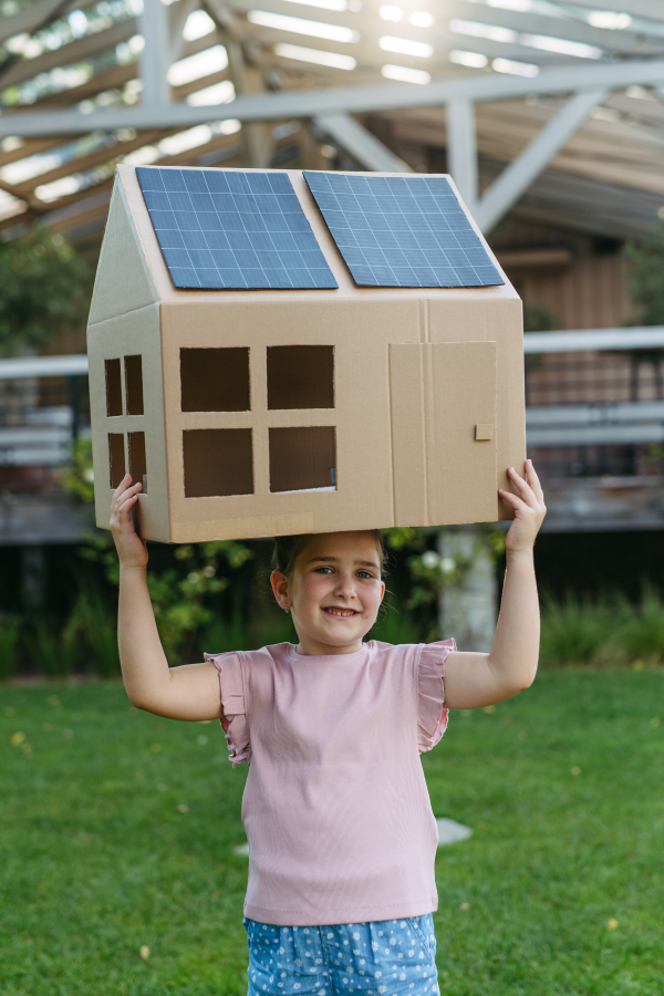 Girl playing with house with solar panels on roof, learning about solar energy. Rooftop solar or photovoltaic system. Sustainable future for next generation concept.