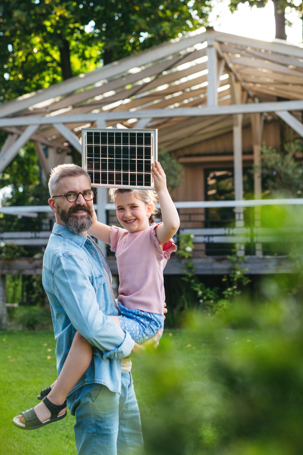 Father and girl in garden, holding model of solar panel. Sustainable future for next generation.