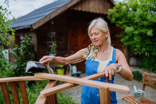 A senior woman cleaning garden furniture and getting the garden ready for summer