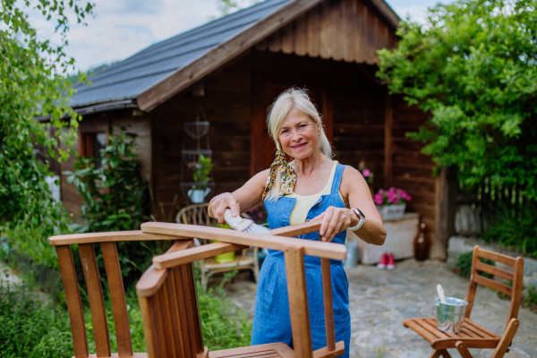 A senior woman cleaning garden furniture and getting the garden ready for summer