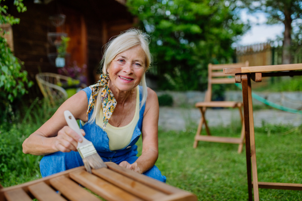 A senior woman cleaning garden furniture and getting the garden ready for summer