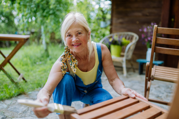 A senior woman cleaning garden furniture and getting the garden ready for summer