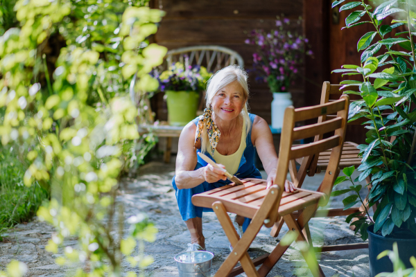 A senior woman cleaning garden furniture and getting the garden ready for summer