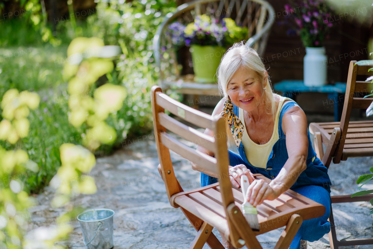 A senior woman cleaning garden furniture and getting the garden ready for summer