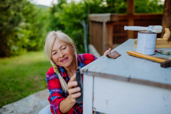 A senior woman cleaning garden furniture and getting the garden ready for summer