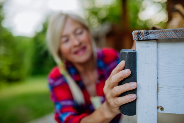 A senior woman cleaning garden furniture and getting the garden ready for summer