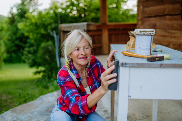 A senior woman cleaning garden furniture and getting the garden ready for summer