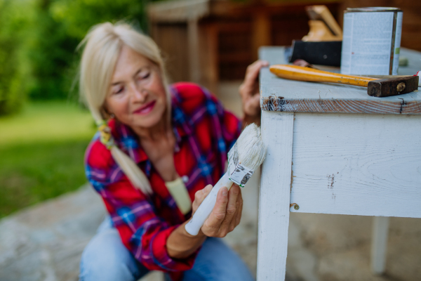 A senior woman cleaning garden furniture and getting the garden ready for summer