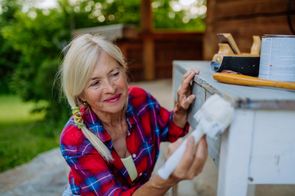 A senior woman cleaning garden furniture and getting the garden ready for summer