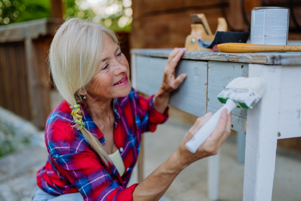 A senior woman cleaning garden furniture and getting the garden ready for summer