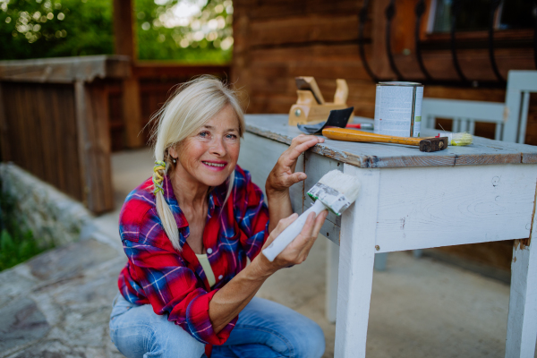 A senior woman cleaning garden furniture and getting the garden ready for summer