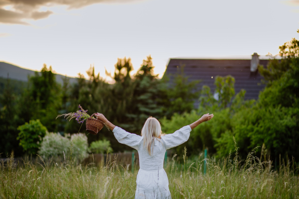 A rear view of senior woman with arms outstretched and face up at park on summer day, mental health concept.