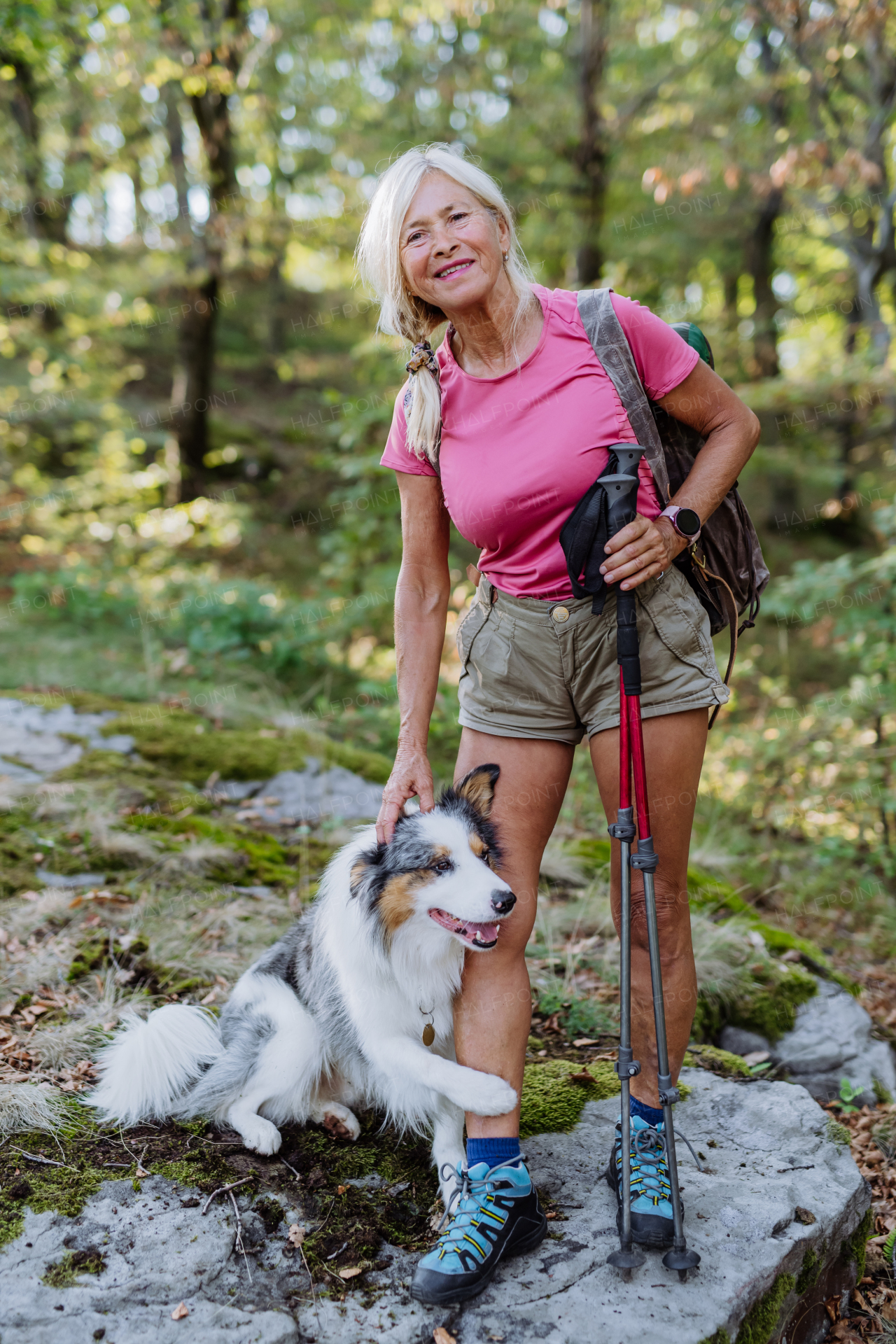 Senior woman walking with her three dog in a forest.