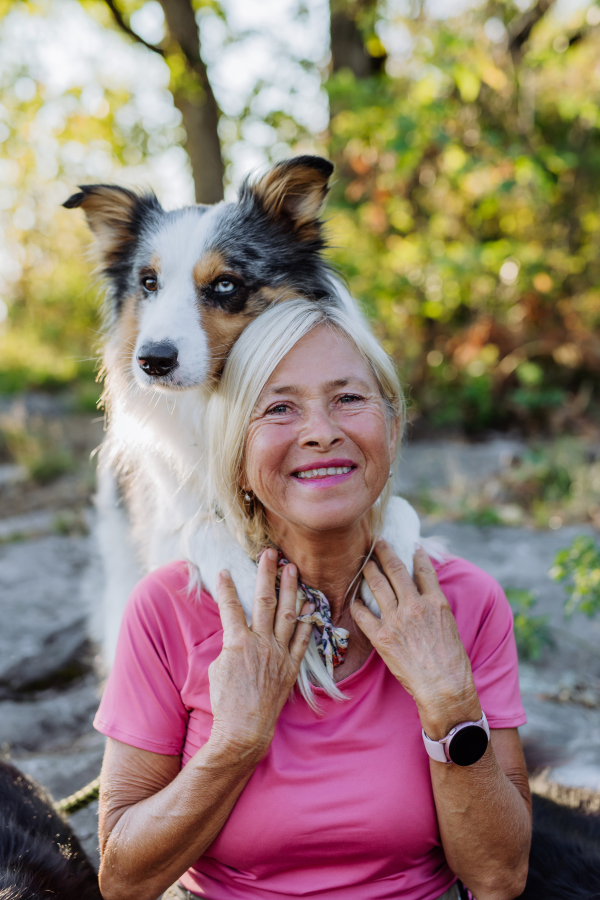 Portrait of senior woman with her dog in a forest.