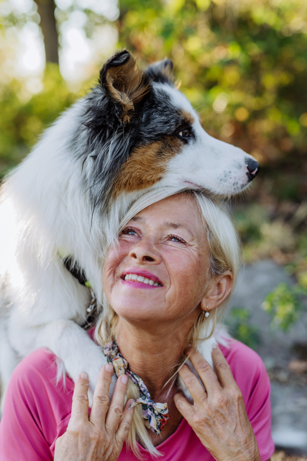 Portrait of senior woman with her dog in a forest.