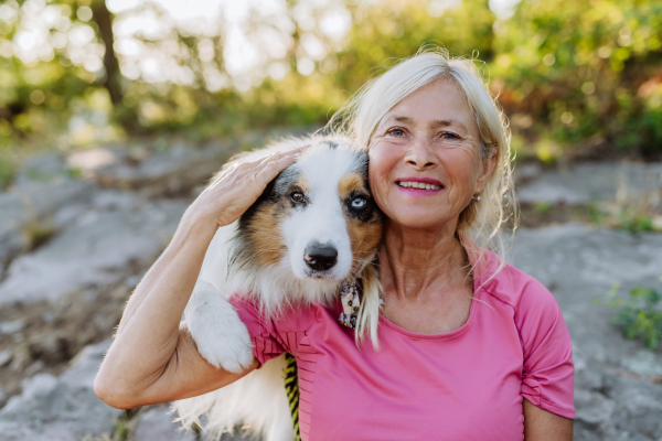 Portrait of senior woman with her dog in a forest.